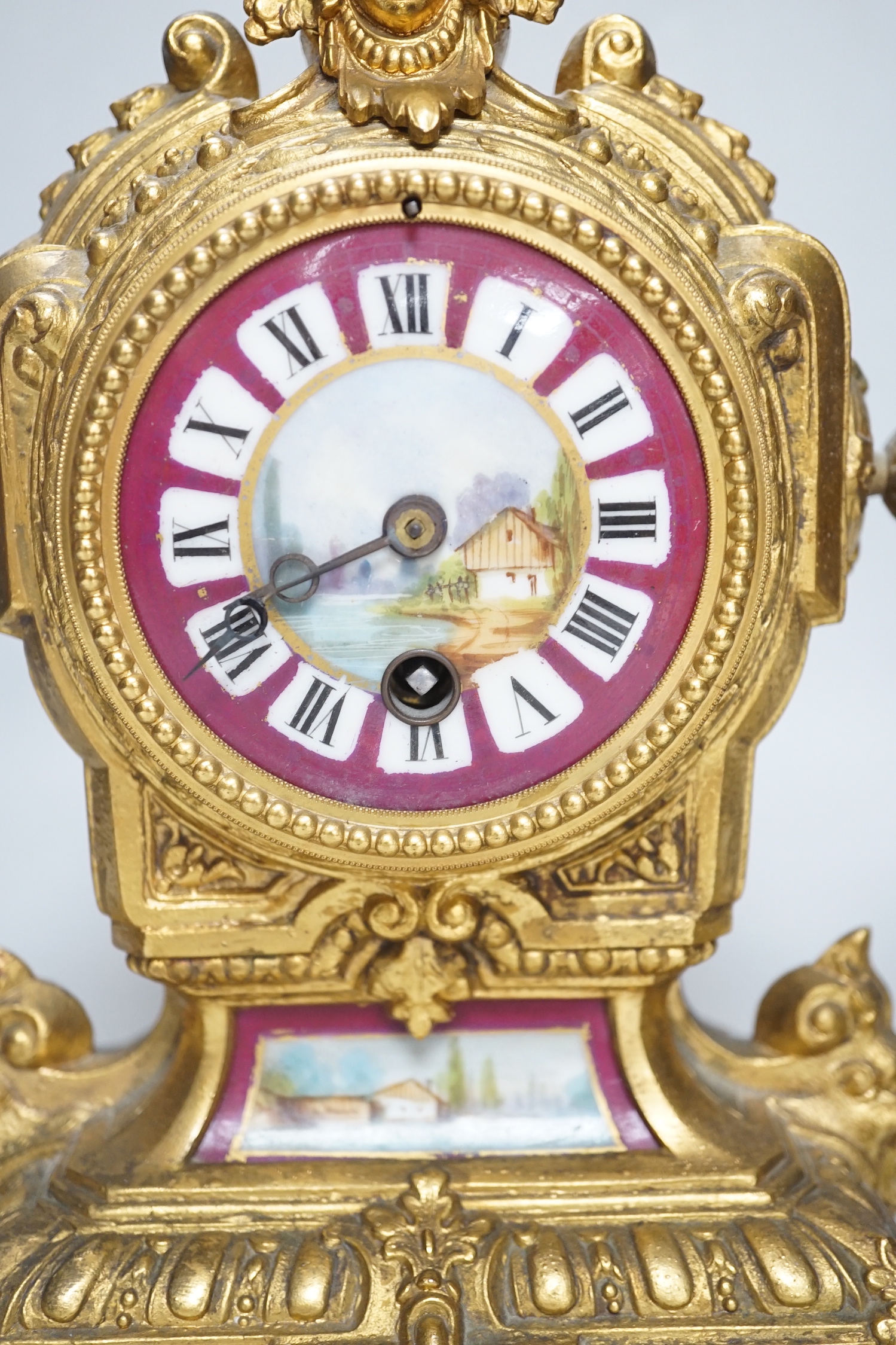 A 19th century porcelain mounted gilt spelter clock garniture, hand painted with landscapes, 30cm high